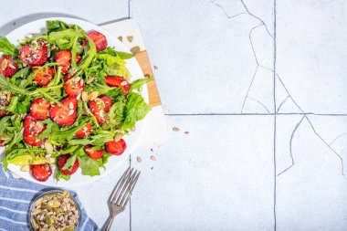 Yaz sağlıklı yemekleri, çilekli roka salatası. Taze diyet çilek salatası roka, ıspanak, marul, çeşitli fındık ve tohumlar, beyaz fayans arka planında fotokopi alanı