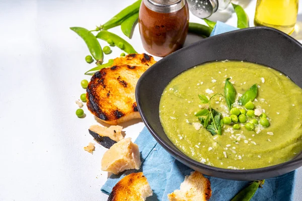 Homemade green pea cream soup, green gazpacho cold soup with peas decor and croutons, tasty vegan food, diet dinner recipe