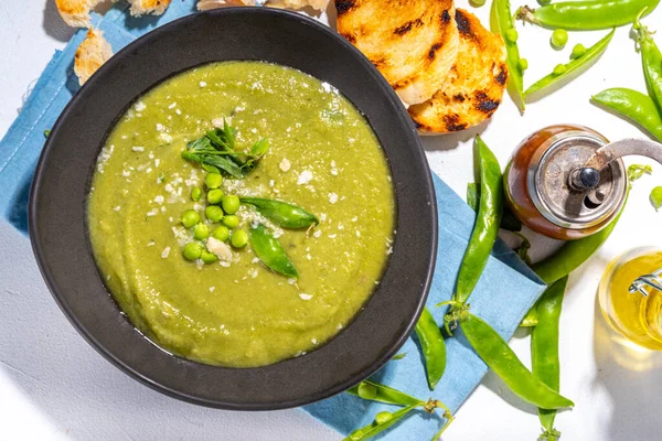 Homemade green pea cream soup, green gazpacho cold soup with peas decor and croutons, tasty vegan food, diet dinner recipe