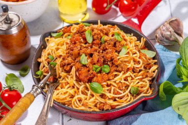 Bol soslu klasik bolonez makarna, dökme demir tavada, geleneksel et soslu İtalyan makarnası parmesan peyniri ve fesleğen yapraklı.