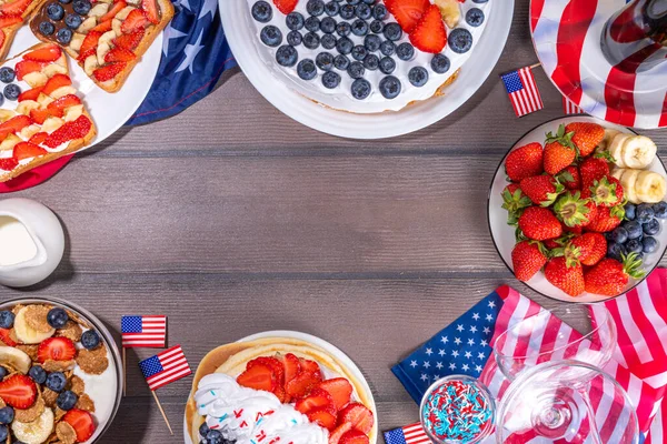 Fourth of July, Patriotic Independence day desserts.  4th of July sweet brunch food and snacks - toast sandwiches, flakes with berries, cake, pancakes, champagne with glasses, holiday decor, flags