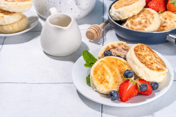 stock image Cottage cheese pancakes, syrniki with fresh berries, sweet summer breakfast. Pan fried roasted portioned cheesecakes 