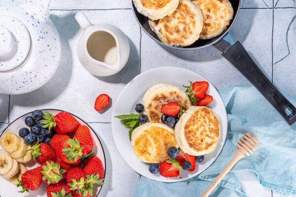 Cottage cheese pancakes, syrniki with fresh berries, sweet summer breakfast. Pan fried roasted portioned cheesecakes 