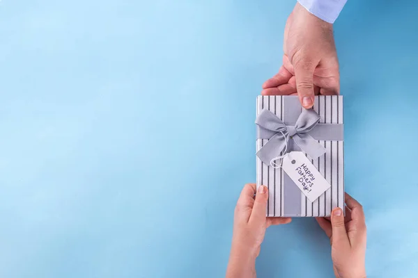 父亲节给可爱的惊喜礼物 最小的简单横幅背景 手和爸爸的手拿着礼品盒 上面有蝴蝶结和 父亲节快乐 的标签 — 图库照片