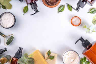 Natural organic skin care flat lay. Natural organic beauty cosmetic products on white background: hand lotion, face cream in jar, essential oil, skin roller, with eucalyptus and tea tree leaves