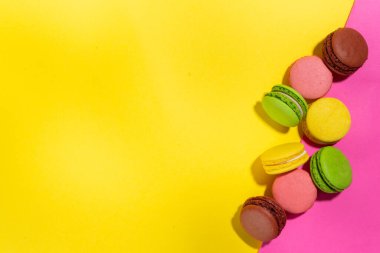 Parlak renkli (sarı, pembe, yeşil, kahverengi) çeşitli aromalı kurabiyeler yüksek renkli pembe arka planda tatlı kurabiyeler. Bir yığın küçük Fransız Makaronlu Kek, Boşluk Dizini Kopyala 