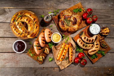 Bavyera sosisi, yuvarlak, gumberland, ketçaplı sucuk, hardal barbekü sosu. Çeşitli bbq ızgara sosisler ahşap arka planda yatıyordu. Sokak festivali ızgara yemek menüsü. 