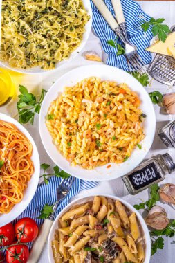 Beyaz fayanslı arka planda farklı soslu makarna seti. Spagetti, farfalle, makarna, deniz ürünleri, ıspanak, karbonara, domates soslu fusilli makarna. İtalyan yemeği, Akdeniz yemeği konsepti