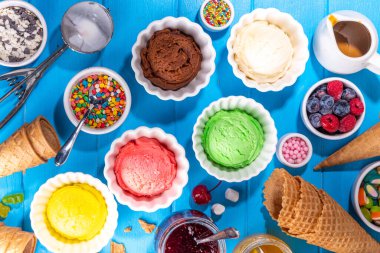 Ice cream festival background, Summer ice cream buffet with various gelato sundaes flavors. sweet toppings and sprinkles, high-colored blue wooden background to view copy space