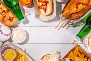 Geleneksel spor stadyumu yemekleri ve bira arka planı, çeşitli beyzbol, basketbol, futbol fanatikleri ve stadyum atıştırmalıkları, cips, sos, bira şişeli sosisliler ve fan aksesuarları. 