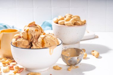 Fıstık ezmeli dondurma topları. Bir sürü fındık dondurması seramik kasede karamelli sos, beyaz mutfak arka plan fotokopi alanı.