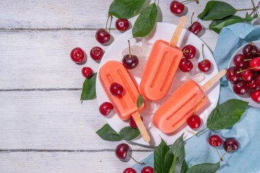 Kirazlı yoğurtlu dondurma lolipoplar, taze kirazlı meyveli dondurma, beyaz ahşap arka plan fotokopi alanı.