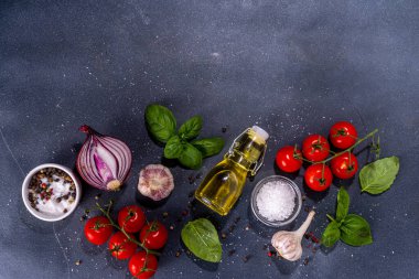 İtalyan yemekleri pişirmek için kullanışlı bir arka plan - domates, fesleğen yaprağı, yeşiller, zeytin yağı, tuz, biber, sarımsak, düz siyah beton masa üstü görünüm alanı 