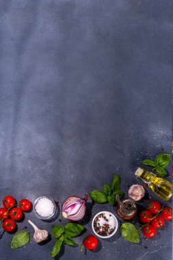 İtalyan yemekleri pişirmek için kullanışlı bir arka plan - domates, fesleğen yaprağı, yeşiller, zeytin yağı, tuz, biber, sarımsak, düz siyah beton masa üstü görünüm alanı 