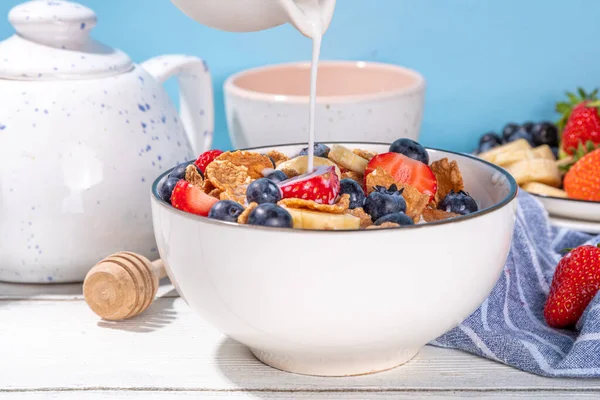 Healthy vitamin diet summer breakfast. Cereal Multigrain  flakes with yogurt or milk and strawberries, blueberries, on kitchen table copy space