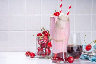 Krema, dondurma, soğuk kola, taze kiraz ve şuruplu ev yapımı vişneli milkshake.