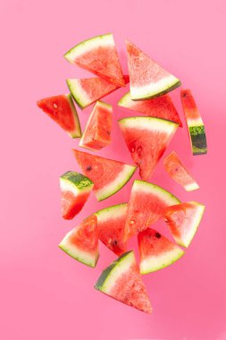 Renkli pembe arka planda dizilmiş karpuz dilimleri. Basit yaz hasadı ve tatil geçmişi, en üstteki düz görünüm afiş alanı