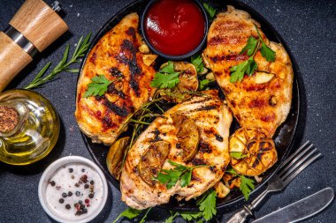 Kızarmış tavuk, hindi fileto. Baharatlı bbq kızarmış beyaz et, sarımsaklı, biberiyeli, limonlu, ketçap soslu, arka planda siyah beton masa arkaplanlı, kemiksiz fileto.