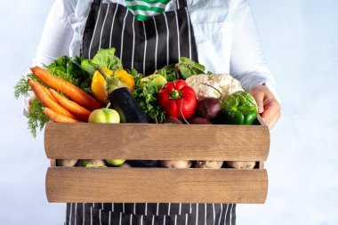 Çiftlik organik pazar alışverişi, yaz, sonbahar çiğ sebze ve meyveli ahşap kutu, çiftçi kadınların elleri beyaz arka planda.