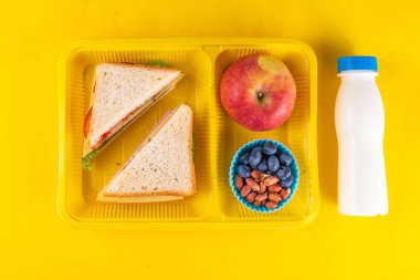 Sağlıklı okul yemekleri, çocuklar beslenme çantasına meyve, böğürtlen, fındık ve sebzeli sandviç koydu. Çocuk diyeti, okul malzemeleri, parlak mavi arka plan, fotokopi alanı.