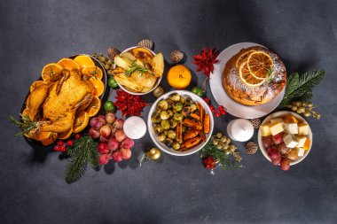 Noel ya da Yeni Yıl yemeği karanlık masada. Geleneksel Xmas parti yemekleri - pannetone, fırında tavuk, sebze, patates, peynir ve meyve tabağı, üst görünüm fotokopi alanı