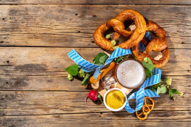 Oktoberfest holiday greeting card, menu, invitation background, Traditional Oktoberfest festival food, bavarian sausages, pretzels, potato, sauerkraut, beer mug on wooden background, copy space above