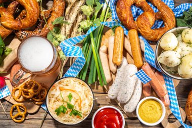 Oktoberfest holiday greeting card, menu, invitation background, Traditional Oktoberfest festival food, bavarian sausages, pretzels, potato, sauerkraut, beer mug on wooden background, copy space above