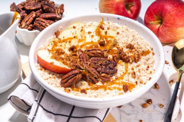 Basit bir sonbahar geleneksel Amerikan kahvaltısı. Elmalı yulaflı yulaf lapası, elmalı, cevizli ve karamelli beyaz masa arkası fotokopi masası.