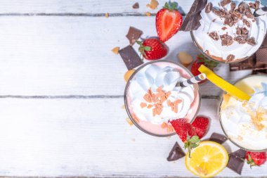 Yaz tazeleyici milkshake seti ya da klasik lezzetli tadı olan meyve suları vanilya limonu, çilek, çikolata, krem şanti ve malzemelerle beyaz, açık mavi, güneşli bir arka planda. 