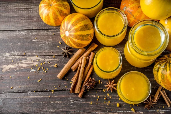 Autumn winter food. Pumpkin puree in different glass jars,with spices, Wooden background copy space
