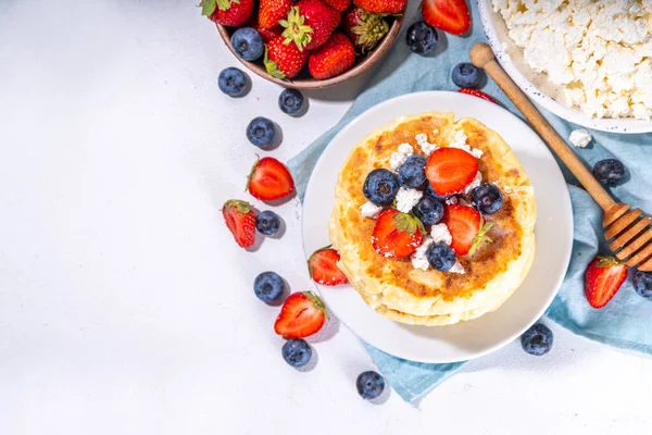 stock image Sweet homemade cottage cheese pancakes, american version of syrniki or cottage cheese fritters, big pan fried cheesy pancakes with fresh summer blueberry and strawberry, healthy high-protein breakfast