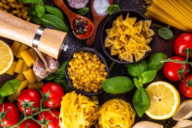 Baharatlı makarna ve yemek pişirmek için malzemeler. Hazırlık yemeği, öğle yemeği arkaplanı taze fesleğen, domates, baharat, sarımsak ve farklı çeşitte İtalyan Akdeniz makarnası.