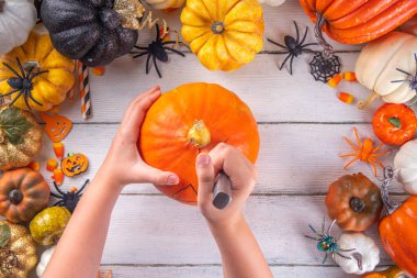 Balkabağı oyma Jack Feneri ile Cadılar Bayramı hazırlığı. Kadın, kadın ve çocuklar ellerini çerçeveye koyar, dekore eder, çizer ve korkunç Cadılar Bayramı partisini oyar.