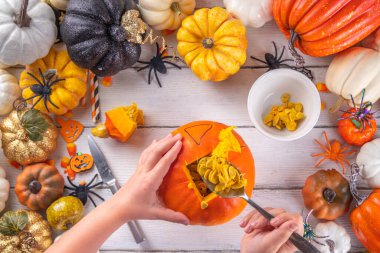 Balkabağı oyma Jack Feneri ile Cadılar Bayramı hazırlığı. Kadın, kadın ve çocuklar ellerini çerçeveye koyar, dekore eder, çizer ve korkunç Cadılar Bayramı partisini oyar.