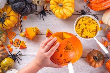 Balkabağı oyma Jack Feneri ile Cadılar Bayramı hazırlığı. Kadın, kadın ve çocuklar ellerini çerçeveye koyar, dekore eder, çizer ve korkunç Cadılar Bayramı partisini oyar.