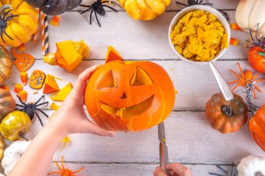 Balkabağı oyma Jack Feneri ile Cadılar Bayramı hazırlığı. Kadın, kadın ve çocuklar ellerini çerçeveye koyar, dekore eder, çizer ve korkunç Cadılar Bayramı partisini oyar.