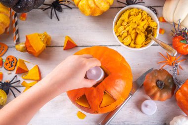 Balkabağı oyma Jack Feneri ile Cadılar Bayramı hazırlığı. Kadın, kadın ve çocuklar ellerini çerçeveye koyar, dekore eder, çizer ve korkunç Cadılar Bayramı partisini oyar.