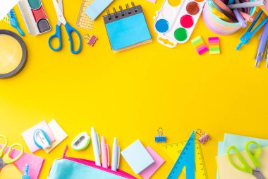 Okul ekipmanları parlak sarı düz yerde yatıyordu. Çeşitli okul ve ofis malzemeleri, aksesuarlar. Okul satışına geri dön. Üst görünüm kopyalama alanı