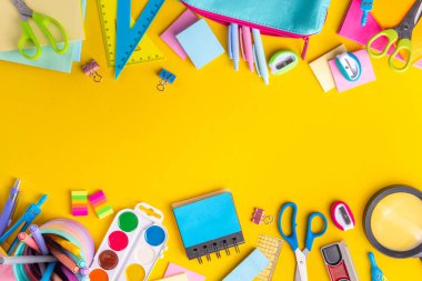 Okul ekipmanları parlak sarı düz yerde yatıyordu. Çeşitli okul ve ofis malzemeleri, aksesuarlar. Okul satışına geri dön. Üst görünüm kopyalama alanı
