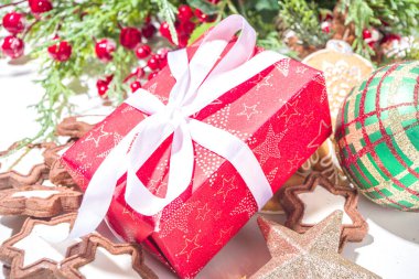 Noel tebrik kartı arka planında Noel ağacı topları, süslemeler, bayram kurdeleli kırmızı hediye kutusu, köknar ağacı, zencefilli kurabiye ve kurabiye, arka planda bokeh etkisi, kopyalama alanı