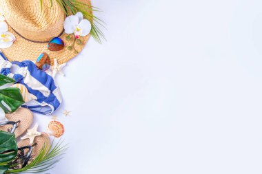 Tropik tatil plajı kaçamağı. Yazlık aksesuarlar, güneş gözlükleri, güneş şapkası, sandaletler, denizyıldızı, palmiye yaprakları, beyaz arka planda fotokopi alanı olan üst manzara