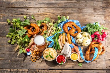 Oktoberfest holiday greeting card, menu, invitation background, Traditional Oktoberfest festival food, bavarian sausages, pretzels, potato, sauerkraut, beer mug on wooden background, copy space above