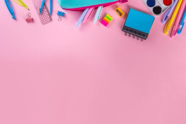 Okul ekipmanları parlak pembe düz yerde yatıyordu. Çeşitli okul ve ofis malzemeleri, aksesuarlar. Okul satışına geri dön. Üst görünüm kopyalama alanı