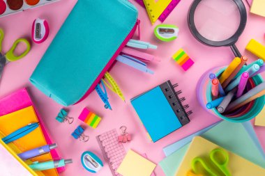 Okul ekipmanları parlak pembe düz yerde yatıyordu. Çeşitli okul ve ofis malzemeleri, aksesuarlar. Okul satışına geri dön. Üst görünüm kopyalama alanı