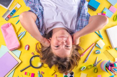 Sevimli duygusal kız okula dönmeye hazır çeşitli okul malzemeleriyle, parlak sarı arka planda eğitim aksesuarlarıyla.