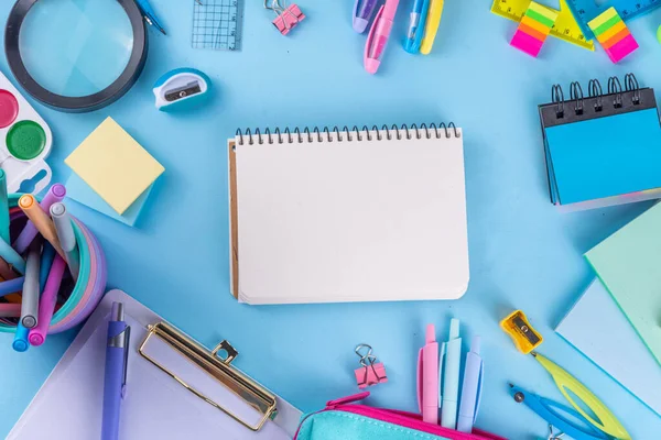 Okul ekipmanları parlak mavi düz yerde yatıyordu. Çeşitli okul ve ofis malzemeleri, aksesuarlar. Okul satışına geri dön. Üst görünüm kopyalama alanı