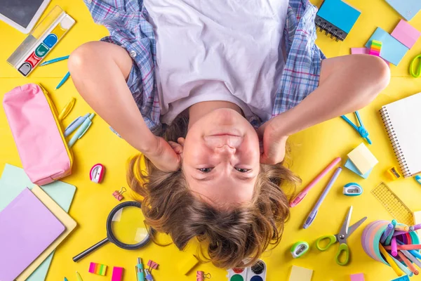 Sevimli duygusal kız okula dönmeye hazır çeşitli okul malzemeleriyle, parlak sarı arka planda eğitim aksesuarlarıyla.