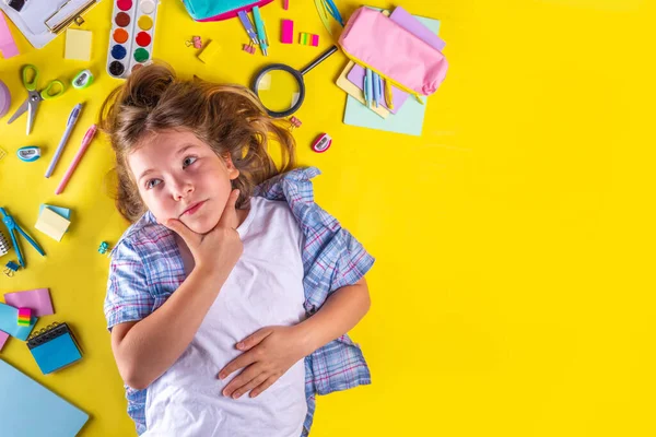 かわいい感情的な少女は さまざまな学校用品 明るい黄色の背景の教育アクセサリーで学校に戻る準備ができています — ストック写真