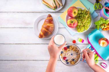 Okul çocukları için sağlıklı besleyici bir sabah kahvaltısı, taze meyve, sebze, kruvasan, müsli, süt ve sandviç. Okul ve iş öncesi kahvaltı yapan kız çocuğu, boşluğu kopyala