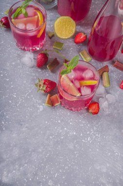 Ev yapımı ravent ve çilekli alkol kokteyli. Rubarb likörü ya da cin, gri bir arka planda taze ravent, çilek, limon, nane